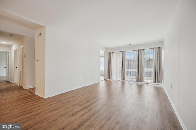 unfurnished room with wood finished floors, visible vents, and baseboards