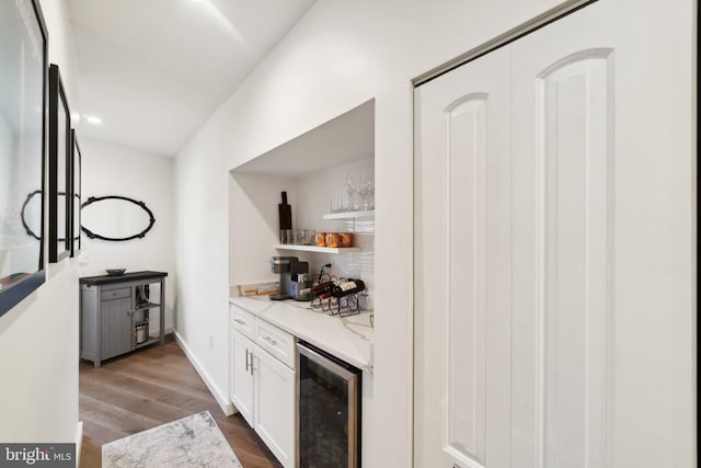 bar featuring beverage cooler, dark hardwood / wood-style flooring, light stone countertops, and white cabinets