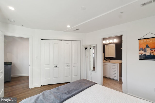 bedroom with hardwood / wood-style flooring, ensuite bath, sink, and a closet