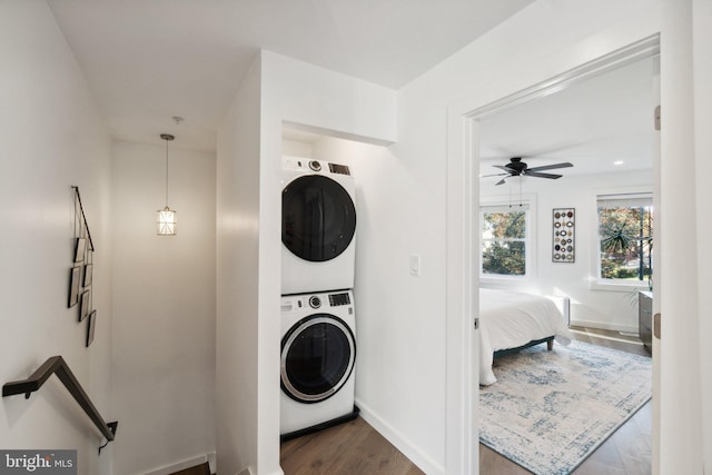 laundry area with stacked washer / drying machine, wood-type flooring, and ceiling fan