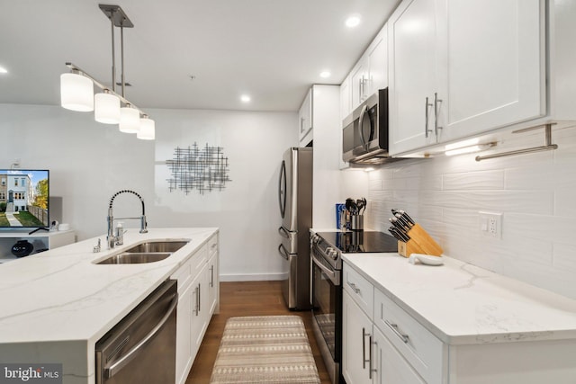 kitchen featuring sink, white cabinets, decorative backsplash, hanging light fixtures, and stainless steel appliances