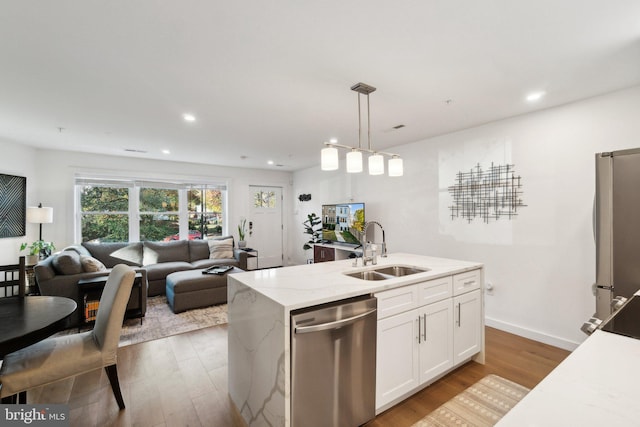 kitchen featuring appliances with stainless steel finishes, pendant lighting, white cabinetry, an island with sink, and sink