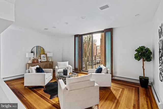 living room with floor to ceiling windows, a baseboard heating unit, and light hardwood / wood-style flooring