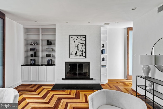 living room with built in shelves, a fireplace, and light parquet floors