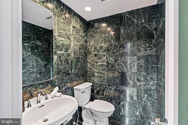 bathroom featuring tile walls, sink, and toilet