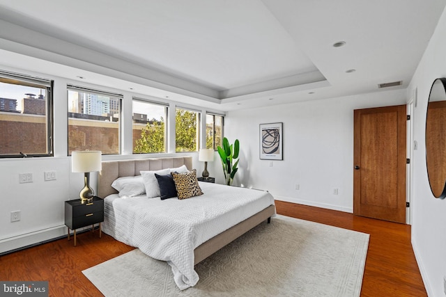 bedroom featuring a raised ceiling and dark hardwood / wood-style flooring