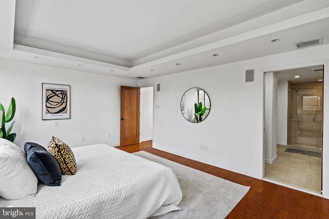 bedroom with wood-type flooring and a tray ceiling