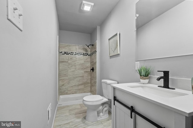 bathroom with vanity, toilet, and a tile shower