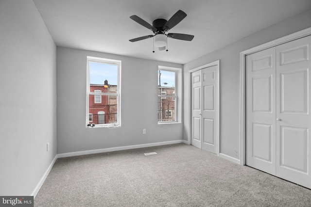 unfurnished bedroom featuring light carpet, two closets, and ceiling fan