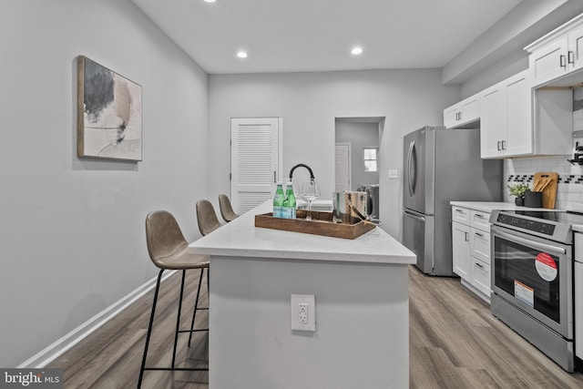 kitchen featuring a kitchen island with sink, a breakfast bar area, stainless steel appliances, and white cabinets