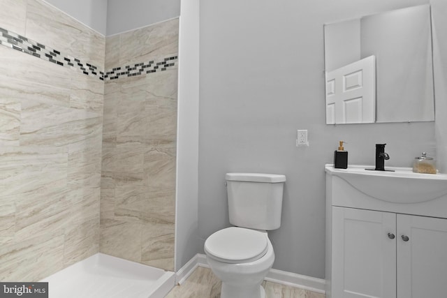 bathroom featuring vanity, toilet, and a tile shower