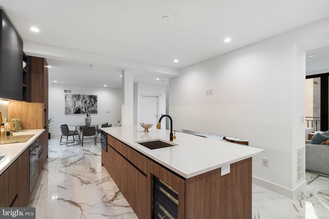 kitchen featuring wine cooler, sink, and a center island with sink