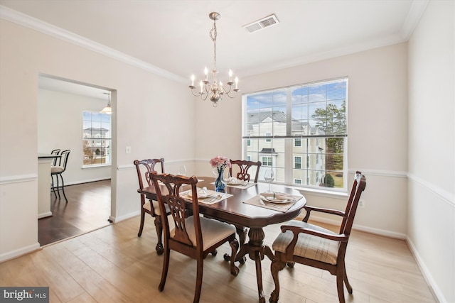 dining area with crown molding, a chandelier, and light hardwood / wood-style flooring