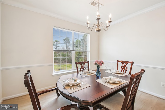 dining space featuring crown molding, an inviting chandelier, and light wood-type flooring