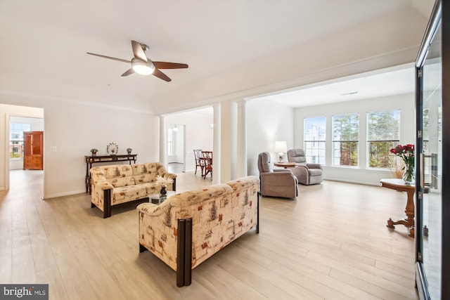 living room featuring ornate columns, ceiling fan, and light wood-type flooring