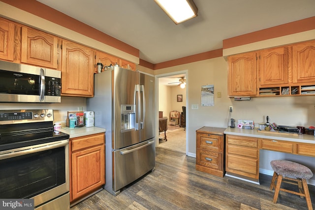 kitchen featuring ceiling fan, stainless steel appliances, dark hardwood / wood-style floors, and built in desk