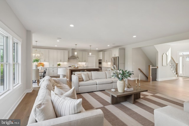 living room featuring sink, a notable chandelier, and light hardwood / wood-style flooring