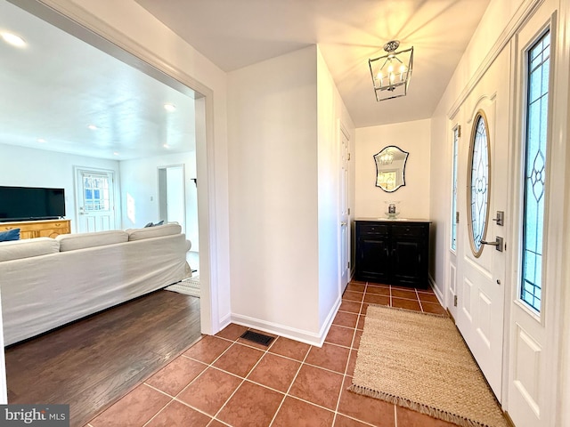 tiled entryway with a notable chandelier