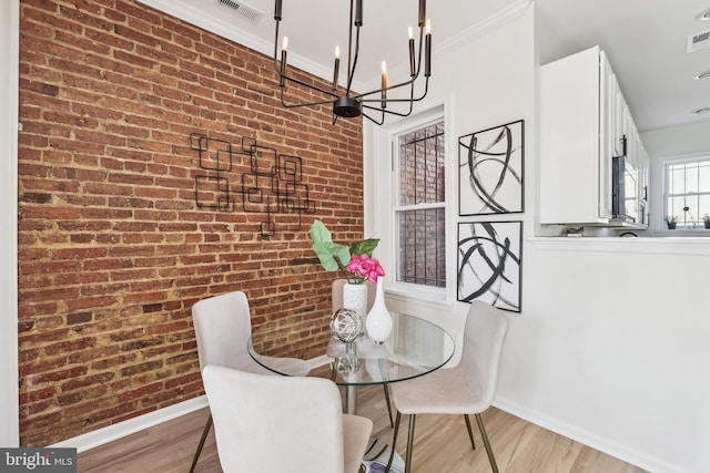 dining room featuring ornamental molding, brick wall, and light hardwood / wood-style flooring