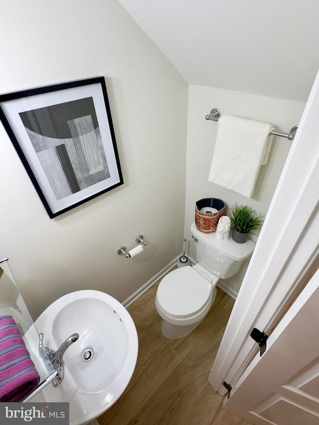 bathroom with hardwood / wood-style flooring, toilet, sink, and vaulted ceiling