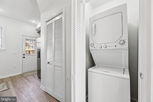 laundry area with stacked washer and dryer and light wood-type flooring