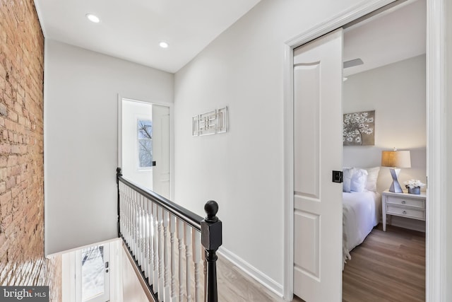 corridor with brick wall and light hardwood / wood-style flooring