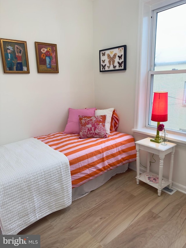 bedroom with multiple windows and light wood-type flooring