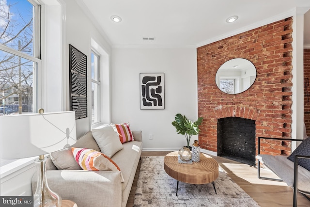 living room featuring ornamental molding, a fireplace, and light hardwood / wood-style floors