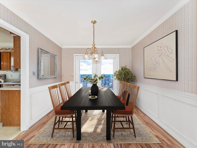 dining room with wallpapered walls, an inviting chandelier, and wainscoting