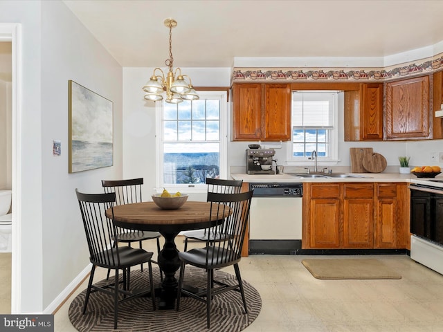 kitchen with pendant lighting, light countertops, brown cabinetry, a sink, and white appliances