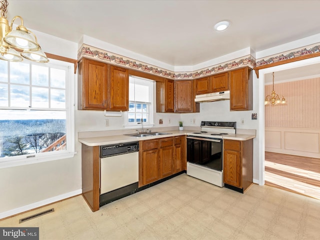 kitchen with white appliances, under cabinet range hood, light countertops, and a sink