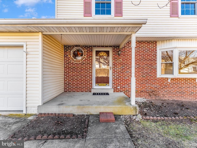 doorway to property with an attached garage and brick siding