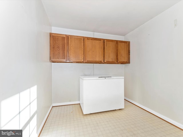 laundry room with light floors, laundry area, and baseboards