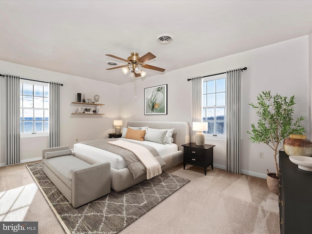 carpeted bedroom featuring a water view, baseboards, visible vents, and ceiling fan