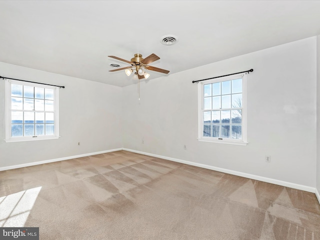 unfurnished room featuring light carpet, a ceiling fan, visible vents, and baseboards