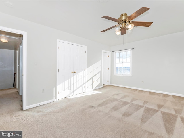 spare room featuring light carpet, a ceiling fan, and baseboards