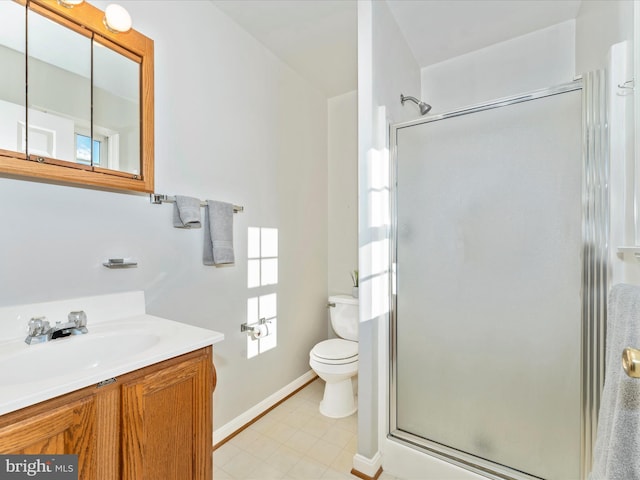 bathroom with a stall shower, baseboards, vanity, and toilet