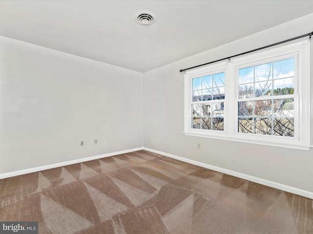 carpeted spare room with visible vents and baseboards