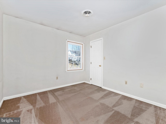 carpeted spare room with visible vents and baseboards