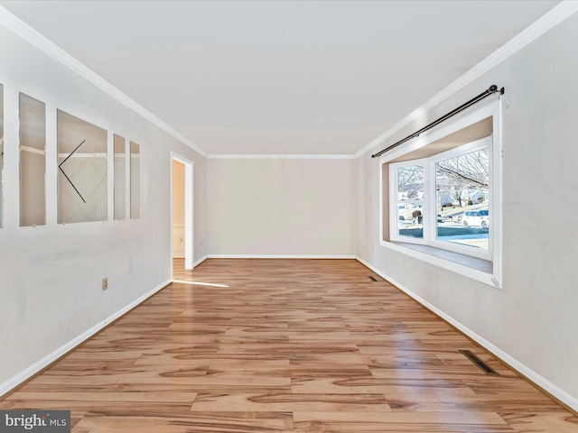 unfurnished room with baseboards, light wood-style floors, visible vents, and crown molding