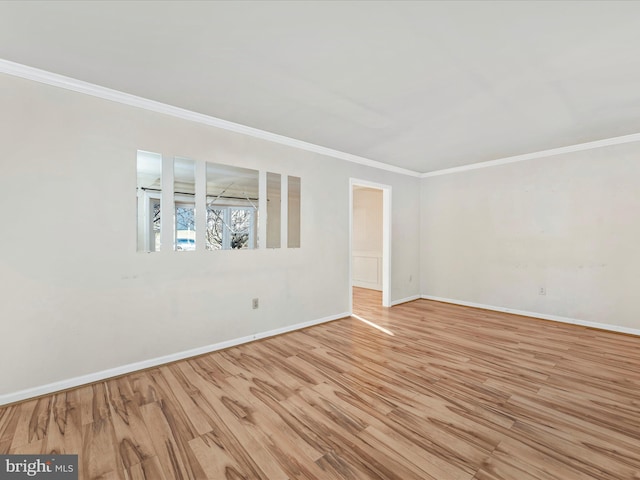 spare room with crown molding, baseboards, and light wood-style floors