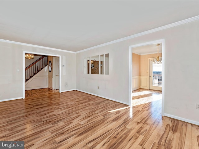 spare room featuring wood finished floors, baseboards, stairs, an inviting chandelier, and crown molding