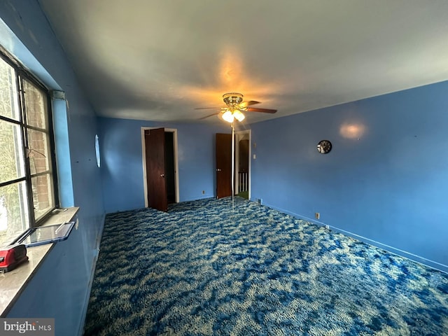 carpeted empty room with ceiling fan and plenty of natural light