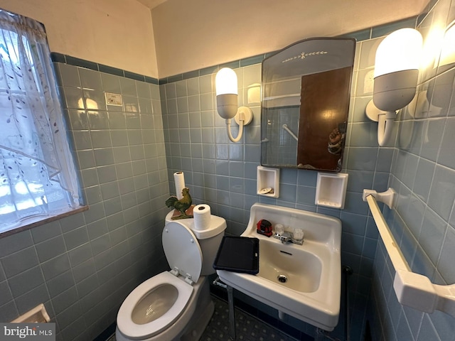 bathroom with sink, tile walls, and toilet