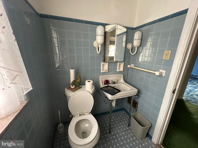 bathroom featuring toilet, tile patterned flooring, sink, and tile walls