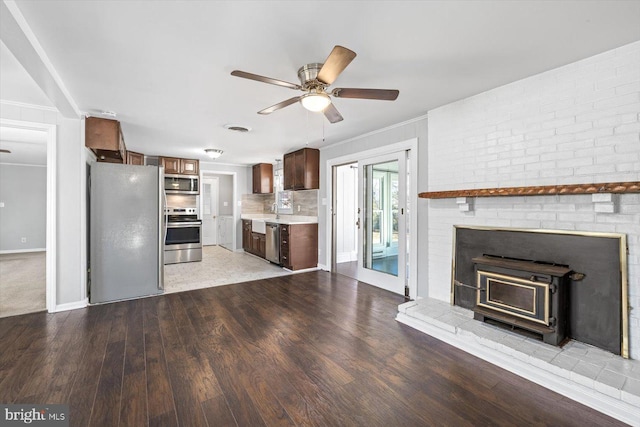 kitchen with crown molding, ceiling fan, appliances with stainless steel finishes, backsplash, and light hardwood / wood-style floors