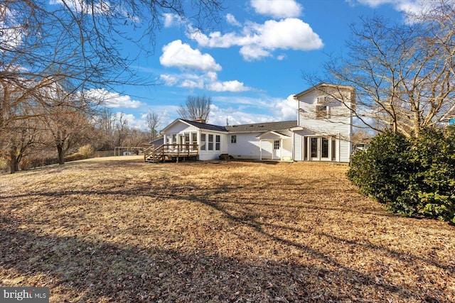 back of property with a deck and a lawn