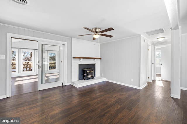 unfurnished living room featuring crown molding, dark hardwood / wood-style floors, a wood stove, and ceiling fan