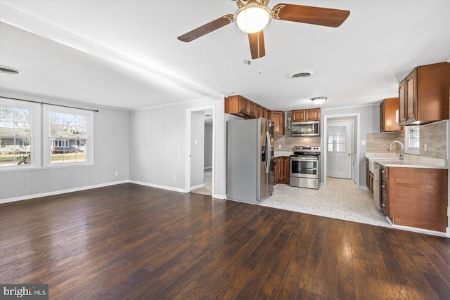 kitchen with tasteful backsplash, stainless steel appliances, light hardwood / wood-style floors, and ceiling fan