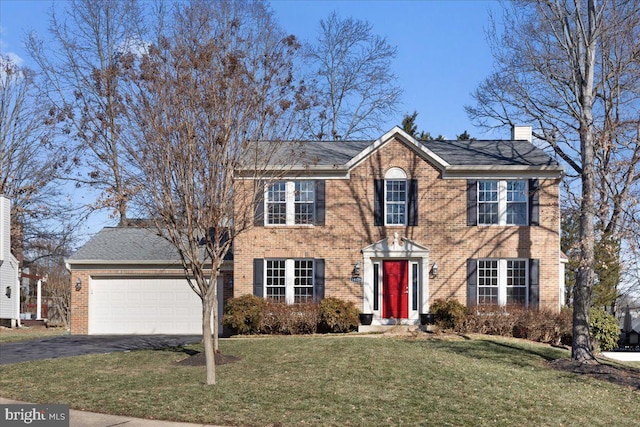 colonial house featuring a garage and a front lawn